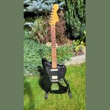 Černá elektrická kytara s černým pickguardem a světle hnědým hmatníkem. Na hlavě je viditelné logo Fender a nápis Japan. Nástroj má dva snímače, tři…