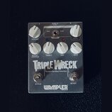 Stříbrný efekt pedál s nápisy TRIPLE WRECK a Modern Rectified Distortion. V dolní části je logo WAMPLER s doplňkem BUILT IN USA. Pedál má šest bílých…