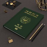 Na fotografii je zelený pas s nápisy v korejsce a angličtině „REPUBLIC OF KOREA“ a „PASSPORT“. Uprostřed je umístěn zlatý státní znak. Vedle pasu lež…