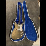 Polodupatá elektrická kytara v zlatavé barvě s bílým pickguardem a dvěma snímači. Na hlavě hmatníku je nápis „Epiphone“ a na pickguardu je logo „Epip…