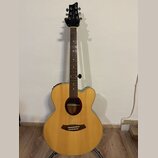 Akustická kytara s cutawayem v přirozené dřevěné barvě a tmavým hmatníkem. Na hlavě je bílý nápis Ibanez a menší text nečitelného modelu. Kytara má t…