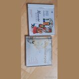Dvě CD v plastových obalech položená na dřevěném povrchu. Horní obal má nápis „Moravské koledy“ a jména „Bambini di Praga z Hradistana“, „Bohumil Kul…
