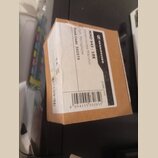 Fotografie znázorňuje hnědou kartonovou krabici s bílou papírovou nálepkou. Na nálepce je uveden nápis SENNHEISER, model MMD 945 - 1BK a popis Dynami…