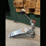 Stříbrný kovový basový pedál s oranžovými detaily na šlapce. Na přední části šlapky je čitelné logo Pearl. Povrch vykazuje mírné známky používání a d…