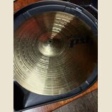 Kovový činel zlaté barvy s koncentrickými rýhami na povrchu. Na pravé straně je modrý nápis pAiste pst 3. Činel je umístěn v černém plastovém obalu.
