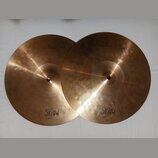 Dva mosazné činely v barvě zlata. Na levém je nápis HI-HAT TOP 13" a logo MAGIC BRONZE. Na pravém je nápis HI-HAT BOTTOM 13" a logo MAGIC BRONZE. Pov…