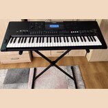 Černý digitální klavír značky YAMAHA, model PSR-E463, umístěný na černém X-stojaně. Nástroj má bílé a černé klávesy a horní panel s displejem, tlačít…