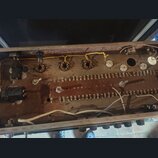 Fotografie zachycuje vnitřek elektronického zařízení, pravděpodobně zesilovače nebo efektu. Je vidět hnědý základ s řadou zapájených součástek, někol…