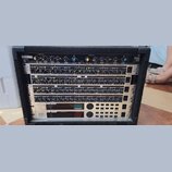 V černém transportním kufru je osazeno několik rackových zařízení značky behringer. Horní jednotka nese nápis Master L / R, CHANNEL ONE, CHANNEL TWO…