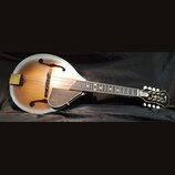 Mandolina s hruškovitým korpusem v přechodovém žlutohnědém odstínu s bílým okrajem. Na hlavě je vidět nápis "Gibson" a dekorativní ornament. Hmatník…