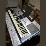 Stříbrný digitální klavír s černobílými klávesami a integrovaným reproduktorem v pravé části. Na ovládacím panelu je viditelné logo YAMAHA a displej.…