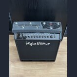 Černý kytarový kombozesilovač s nápisem Hughes & Kettner na předním textilním krytu. Horní ovládací panel obsahuje digitální displej s nápisem BANK a…