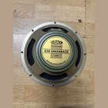 Kruhový reproduktor s kovovým rámem v béžovém odstínu a černou membránou. Uprostřed je žlutý štít s nápisy CELESTION LOUDSPEAKERS, G10 GREENBACK a 30…