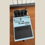 Světle modrý efekt pedál značky BOSS, model Chorus Ensemble CE-5. Na horní části jsou čtyři černé ovládací knoflíky s popisky MIN MAX a CUT FLAT HIGH…