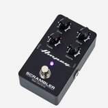 Černý efekt pedál s kovovým šasi. Na horní straně jsou čtyři ovládací knoflíky s popisky Drive, Blend, Treble a Volume, svítící fialová LED kontrolka…