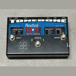 Černý efekt pedál s nápisy TONEBONE, Radial JX-2 PRO a SWITCHBONE. Na horní straně jsou ovládací prvky: dva stisknuté přepínače s popisky BOTH a BOOS…