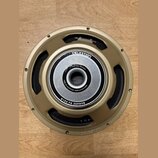 Fotografie znázorňuje reproduktor s kovovým rámem v zlatavé barvě. Na středovém magnetu je bílý nápis CUSTOM DESIGN a FOR BLACKSTAR AMPLIFICATION, po…
