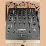 Černý mixážní pult s nápisem Numark a označením M6 USB. Zařízení obsahuje čtyři vstupní kanály (CH1 až CH4) a jeden Master kanál, každý s posuvníkem…