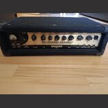 Černý basový zesilovač s kovovým předním panelem. Na panelu je nápis BEHRINGER a model ULTRABASS BX3000T s doplňujícím textem 300-WATT BASS AMPLIFIER…