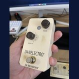Kompaktní efekt pedál v krémové barvě s dvěma černými ovládacími knoflíky. Na pedálu jsou nápisy VOLUME, BREAK-UP a v dolní části značka DANELECTRO®…