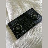 Černý DJ kontrolér s dvěma jog-koly a centrálním mixážním sekcí. Na horní části je bílé logo Pioneer DJ a v pravé části nápis DDJ-400. Povrch přístro…