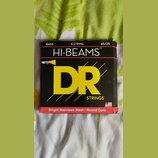 Fotografie znázorňuje krabičku s basovými strunami. Na černém povrchu je žlutý nápis DR STRINGS a bílý text HI-BEAMS™. V horní části je uvedeno BASS,…