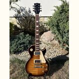 Elektrická kytara s trupem v tmavě hnědé barvě s přechodem do světlejší žluté v centru. Na hlavě hmatníku je bílý nápis Gibson a pod ním kurzivou Les…
