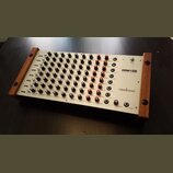 Stříbrný analogový drum synthesizer s dřevěnými bočními panely. Na pravé straně je uveden název modelu DRM1 MK III a značka VERMONA. Přístroj obsahuj…