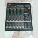 Šedý mixovací pult v transportním kufru. V horní části je logo YAMAHA a nápis MIXING CONSOLE MGP16X. Zařízení obsahuje více kanálů s ovládacími knofl…