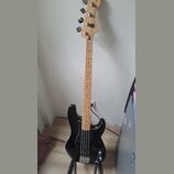 Černá elektrická basová kytara s hnedým javorovým hmatníkem a hlavou. Na hlavě je vidět logo Fender a nápis Precision Bass Special. Nástroj je umístě…