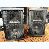 Dva černé reproduktory s kovovými mřížkami včelí struktury. Na spodní části obou reproduktorů je umístěno žluté a bílé logo s nápisem KV audio. Povrc…