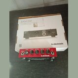 Červený basový zesilovač s nápisy BAM200, INPUT, GAIN, BASS, MIDDLE, TREBLE a MASTER. Na předním panelu je logo tc electronic a text CLASS-D BASS AMP…