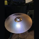 Stříbrný cymbál s koncentrickým žebrováním, umístěný na kovovém stojanu. Na povrchu je černý nápis PAiste 2008 bronze a pod ním text 18" CRASH RIDE.…