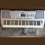 Stříbrný digitální klavír s bílými a černými klávesami. Na horním panelu je v centru logo YAMAHA a vpravo nápis PSR-290. Nástroj obsahuje řadu tlačít…
