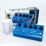 Modrý efekt pedál s nápisy FLASHBACK X4 a tc electronic. Na horní straně jsou čtyři černé ovládací knoflíky, tři spínače a nápisy jako TRUE BYPASS DE…