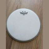 Kruhová bílá naleštěná bubnová blana s matným povrchem. V horní části je černé logo REMO pod stylizovanou korunou a nápisy EMPEROR COATED, MADE IN U.…