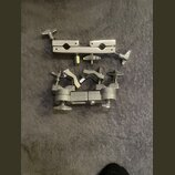 Dvě kovové svorky z nerezové oceli s utahovacími šrouby s křídly. Horní svorka má dvě úchopy a spodní svorka je členěná do několika pohyblivých částí…