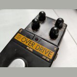 Černý kytarový efekt s nápisem OVER DRIVE na žlutém pozadí. Pod nápisem je uveden text PEARL a označení modelu OD-05. Zařízení má čtyři černé ovládac…