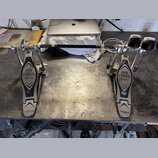 Dvojpedál na bicí buben z kovového materiálu s černými plátmi. Na obou plátích je nápis IRON COBRA 200 a v dolní části logo TAMA. Povrch plátů vykazu…