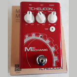 Červený efekt pedál s bílými nápisy a třemi bílými otočnými ovladači. Na horní části je logo TC HELICON a popisky MIC, OUT, POWER, ECHO, REVERB, CORR…