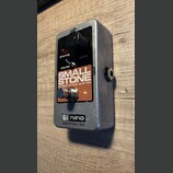 Stříbrný efekt pedál s černým ovládacím panelem a hnědým štítkem. Na štítku je bílý nápis SMALL STONE a pod ním EH4800 PHASE SHIFTER. Na spodní části…