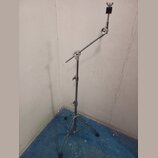 Stříbrný kovový mikrofonní stojan s trojnožkou a výsuvným ramenem. Na horním konci je umístěn černý držák mikrofonu. Povrch stojanu vykazuje známky b…