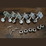 Sada šesti stříbrných kovových ladicích kolínek s kulatými knoflíky. Pod nimi jsou rozložené dvanácti kovové šroubky a šest stříbrných podložek. Všec…