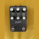 Černý kytarový pedál s nápisem Dream 65 REVERB-AMP a logem ve tvaru stylizovaného písmena v kosočtverci. Zařízení má šest otočných bílo-stříbrných kn…