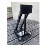 Černý kovový pedál s černou ploščkou. Na spodní základně je viditelné logo Pearl. Předmět vykazuje mírné známky opotřebení povrchu a prach.