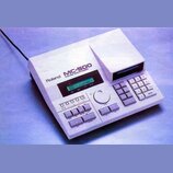 Bílá sekvence s integrovanou disketovou mechanikou. Na horním panelu je nápis Roland MC-500 MICRO COMPOSER a zelený displej s textem SONG 1 MEAS 1 q=…