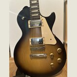 Elektrická kytara s tmelelovým povrchem v přechodové barvě od černé k žluté. Nástroj má dva humbuckery s chromovanými kryty, krémový pickguard a čtyř…