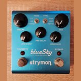 Modře anodizovaný efekt pedál s nápisy blueSky reverberator a strymon. Obsahuje pět černých otočných ovladačů s bílou značkou a dva přepínače typu to…
