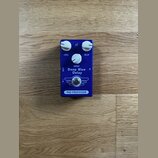 Modrý efekt pedál s bílými ovládacími knoflíky. Na přední straně jsou nápisy LEVEL, DELAY, REPEAT a uprostřed model Deep Blue Delay. Ve spodní části…