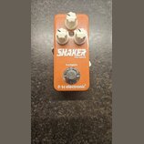 Oranžový efekt pedál s třemi bílými oválnými knoflíky. Na přední straně je bílý nápis SHAKER a pod ním menší text MINI VIBRATO. Pod ním je uveden náp…